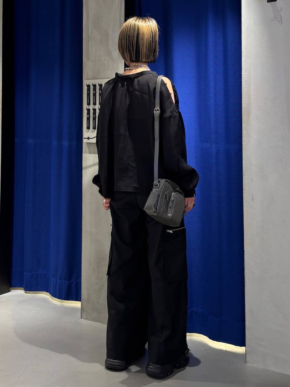 ブラック系のスニーカー、ブラック系のスラックス、グレー系のショルダーバッグを着用したレディースの春コーディネートの4枚目の写真