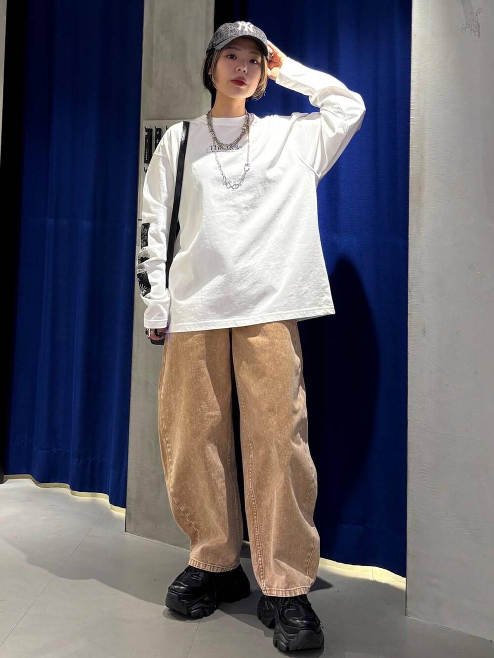 ブラック系のスニーカー、ブラウン系のデニムパンツ、ブラック系のショルダーバッグを着用したレディースの春コーディネートの2枚目の写真