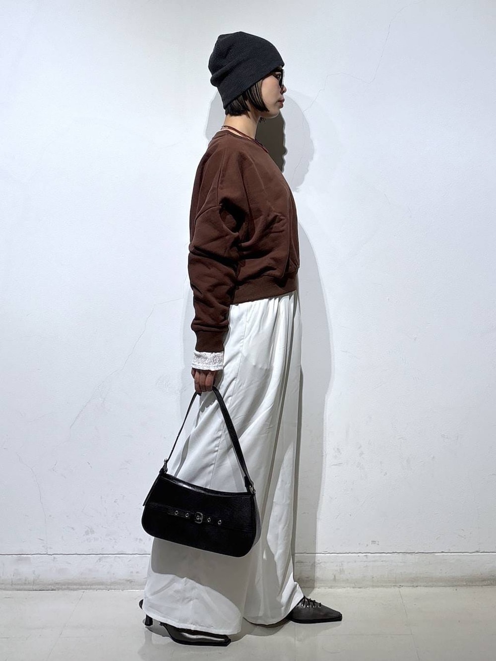 ブラウン系のスウェット、ブラック系のハンドバッグ、ブラック系のサンダルを着用したレディースの春コーディネートの4枚目の写真