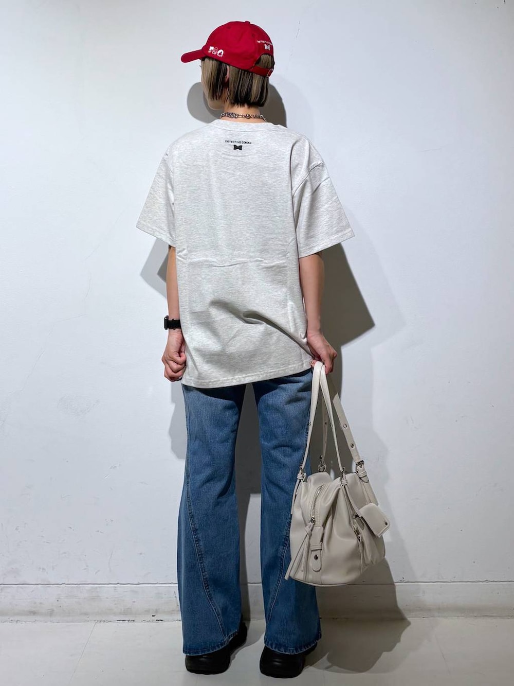 ブラック系のスニーカー、ブルー系のデニムパンツ、ホワイト系のボストンバッグを着用したレディースの春コーディネートの6枚目の写真