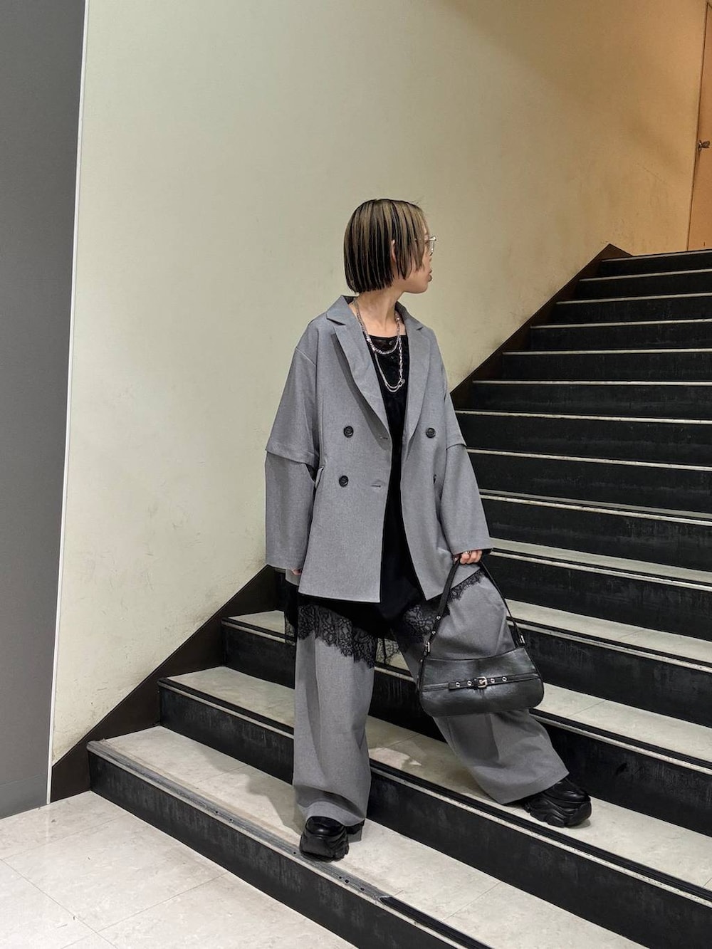 ブラック系のスニーカー、ブラック系のチュニック、ブラック系のハンドバッグを着用したレディースの春コーディネートの6枚目の写真