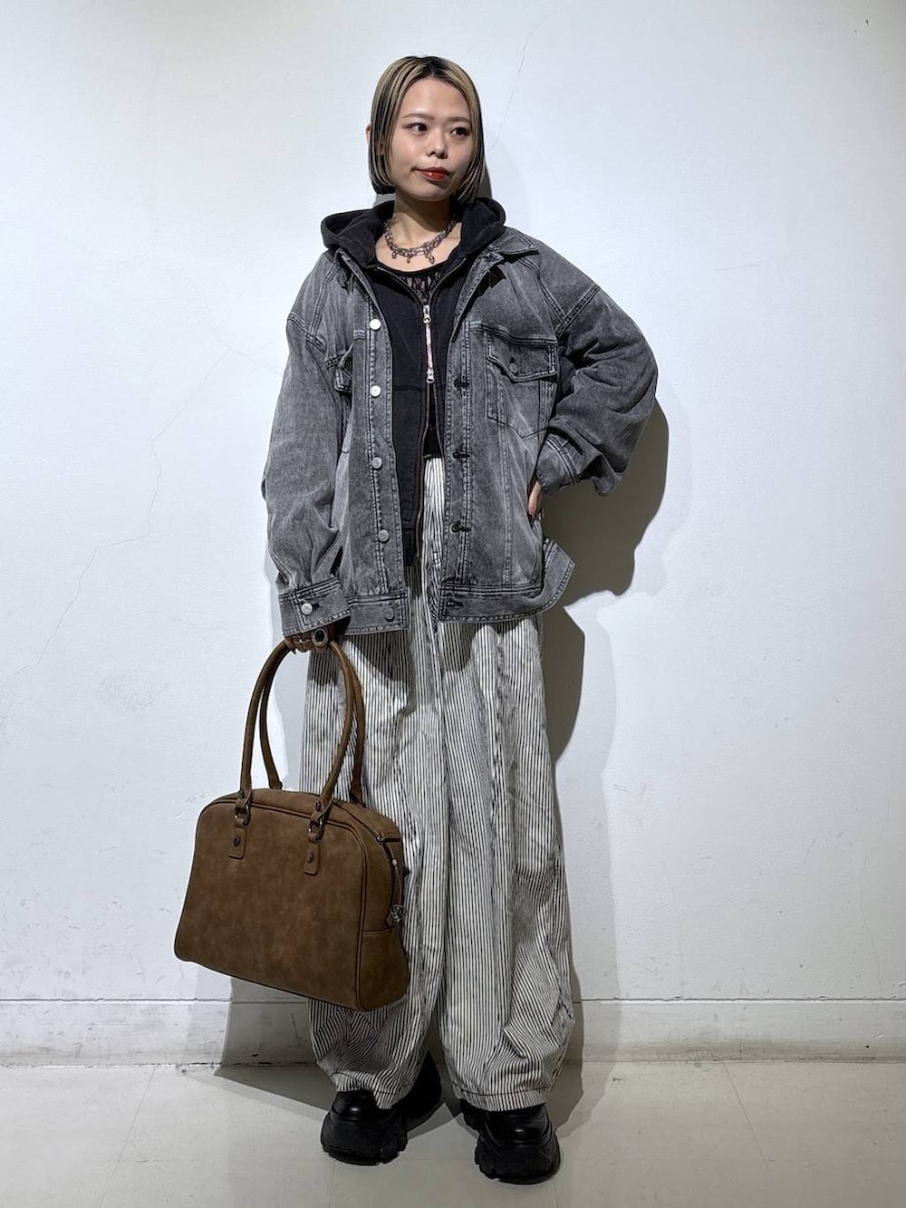 ブラック系のブーツ、ベージュ系のボストンバッグ、ブラック系のTシャツ/カットソーを着用したレディースの冬コーディネートの3枚目の写真