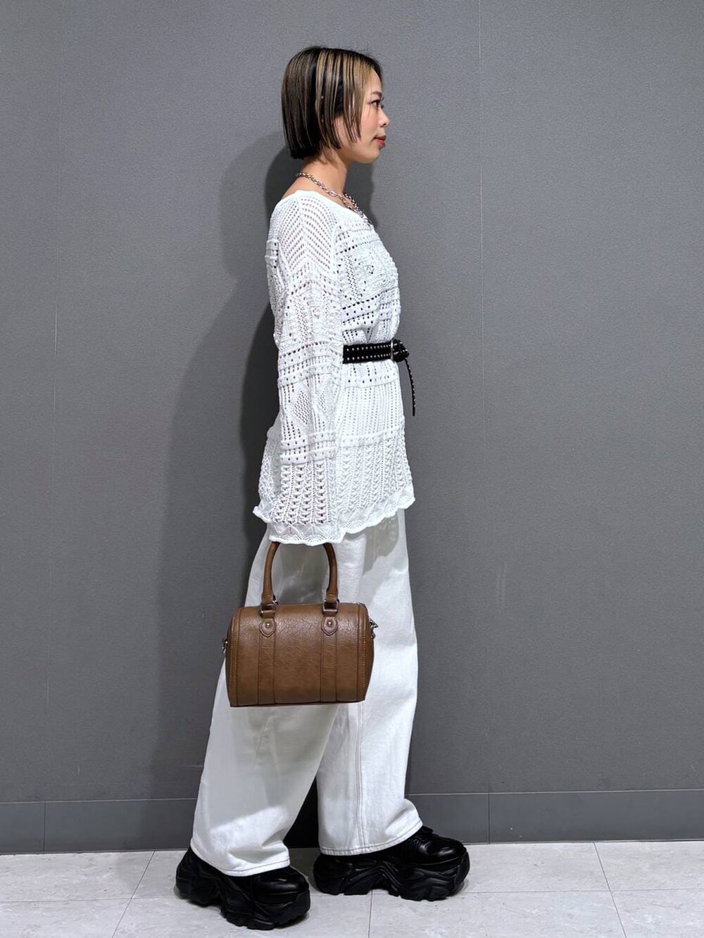 ブラック系のスニーカー、ホワイト系のスラックス、ブラウン系のボストンバッグを着用したレディースの春コーディネートの4枚目の写真