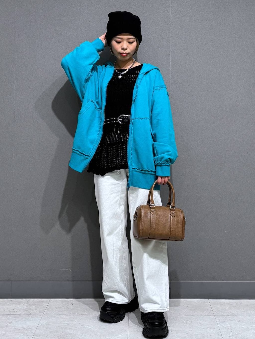 ブラック系のスニーカー、ホワイト系のスラックス、ブラウン系のボストンバッグを着用したレディースの春コーディネートの2枚目の写真