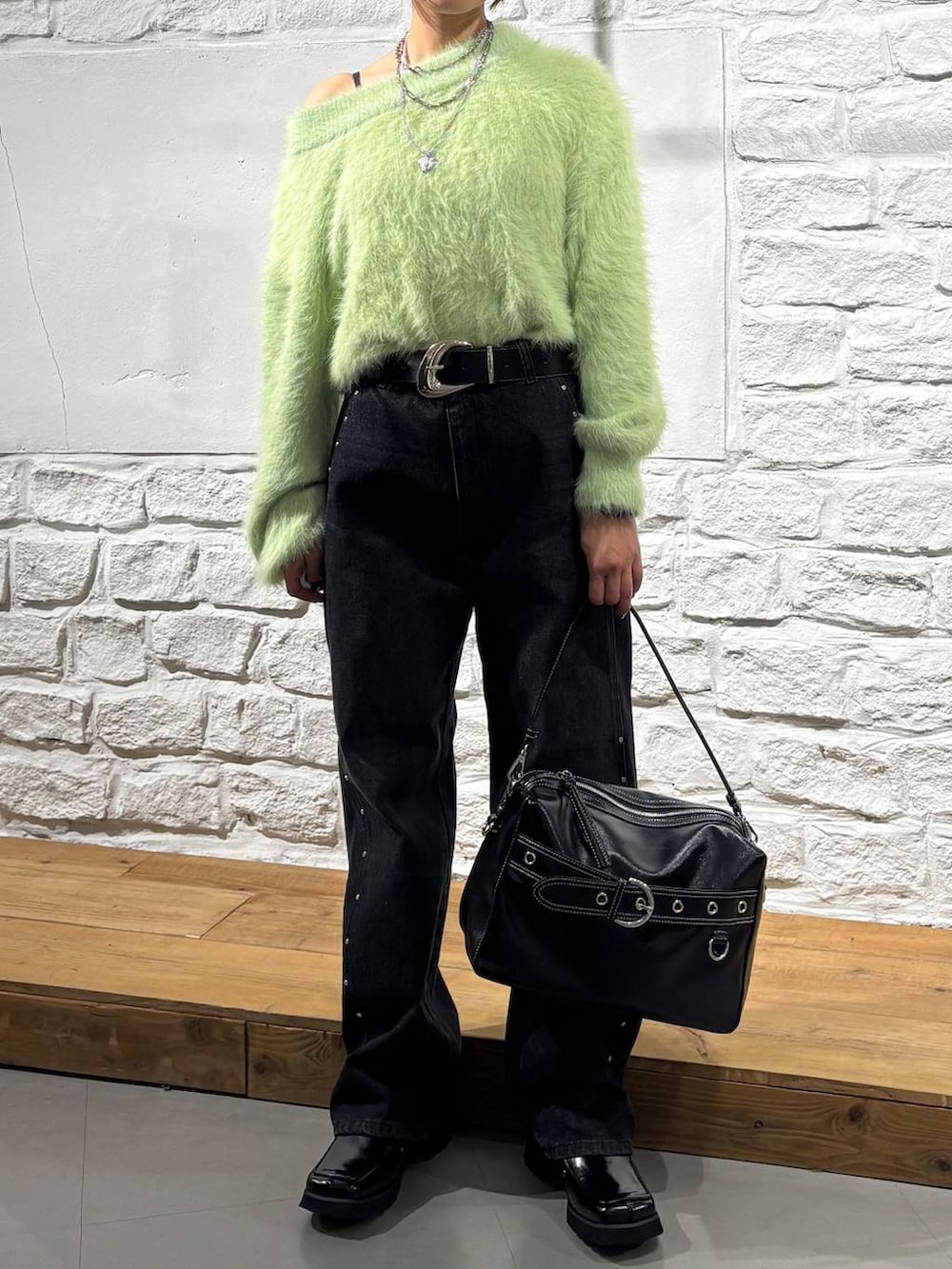 ブラック系のブーツ、ブラック系のデニムパンツ、ブラック系のショルダーバッグを着用したレディースの秋コーディネートの2枚目の写真