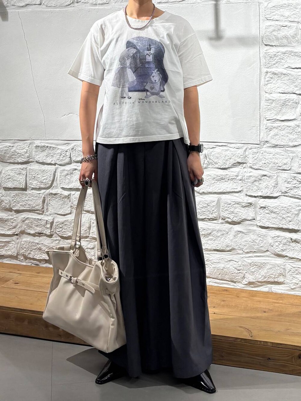グレー系のスラックス、ホワイト系のTシャツ/カットソー、ホワイト系のショルダーバッグを着用したレディースの夏コーディネートの3枚目の写真