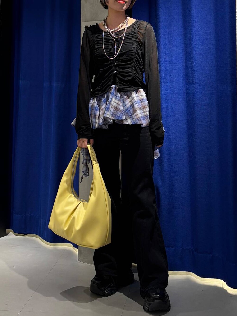 ブラック系のスニーカー、ブラック系のデニムパンツ、イエロー系のトートバッグを着用したレディースの春コーディネートの2枚目の写真