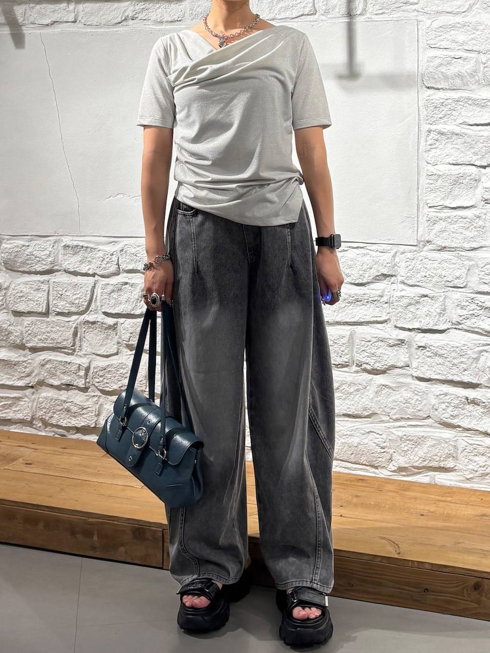 ブラック系のデニムパンツ、グレー系のサンダル、ベージュ系のTシャツ/カットソーを着用したレディースの夏コーディネートの3枚目の写真