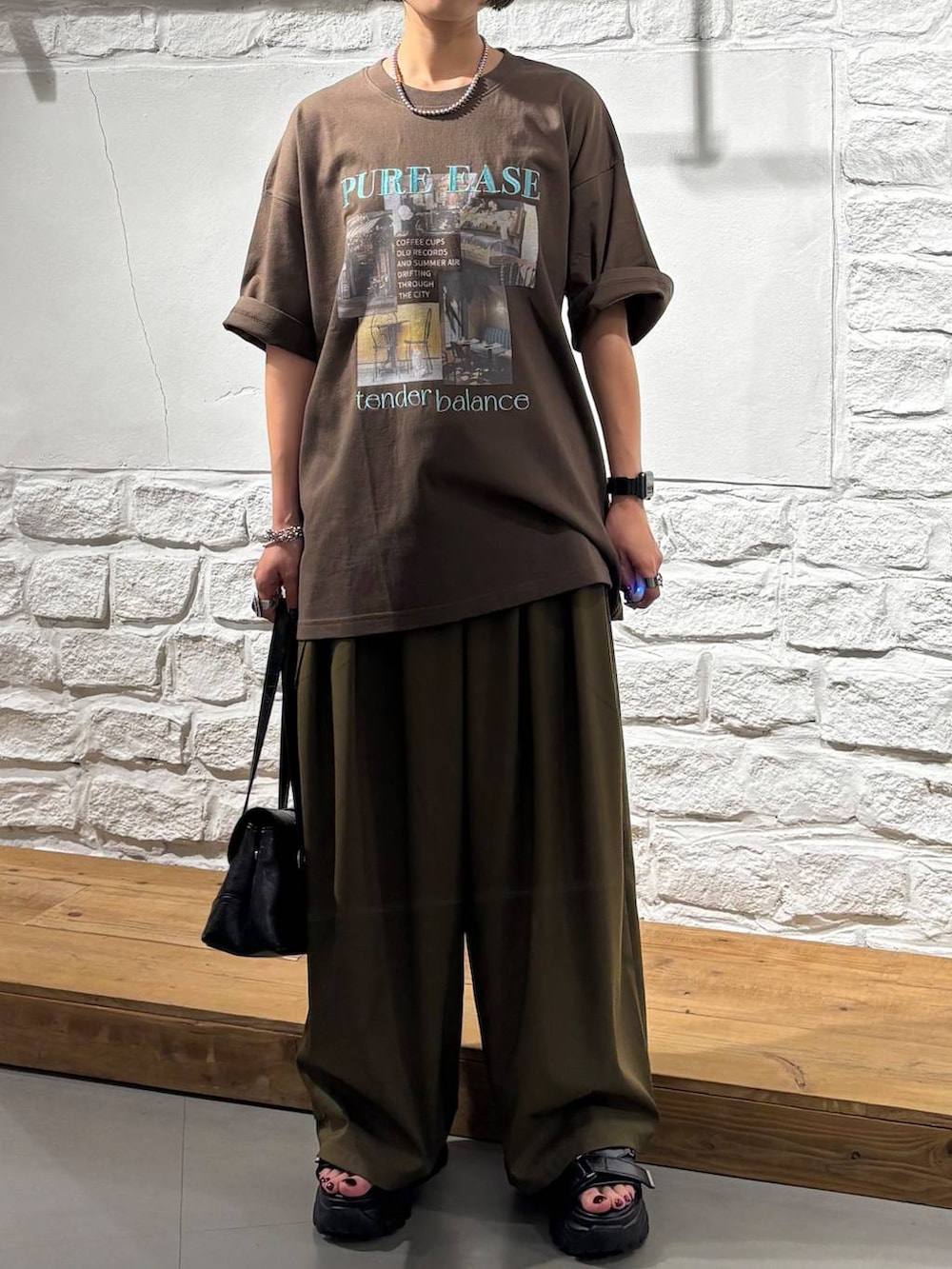 グリーン系のスラックス、ブラウン系のTシャツ/カットソー、ブラック系のサンダルを着用したレディースの夏コーディネートの3枚目の写真
