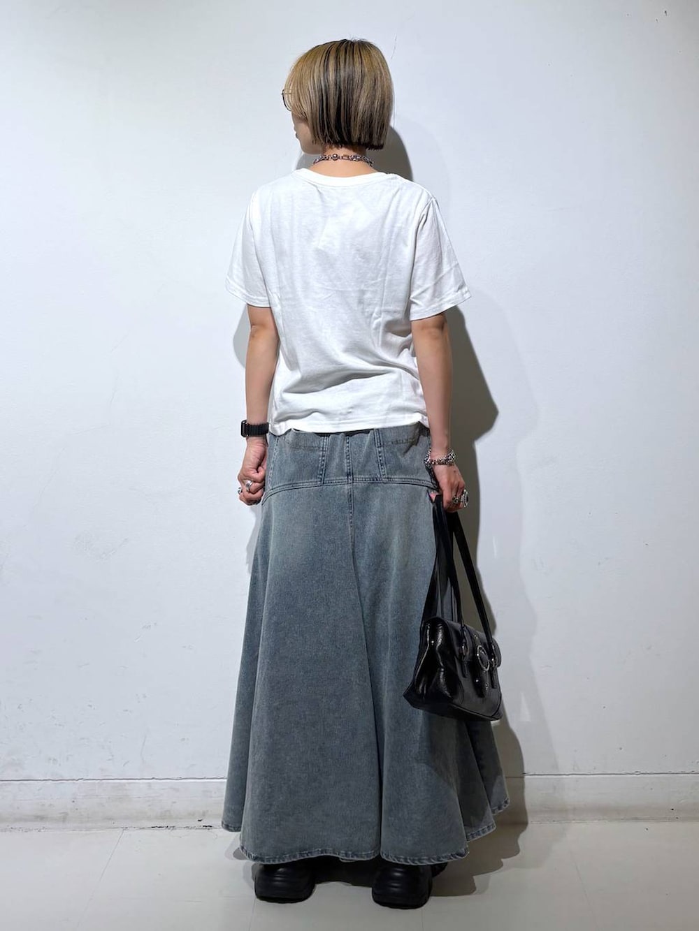 ホワイト系のTシャツ/カットソー、ブラック系のスニーカー、ブルー系のデニムスカートを着用したレディースの夏コーディネートの5枚目の写真