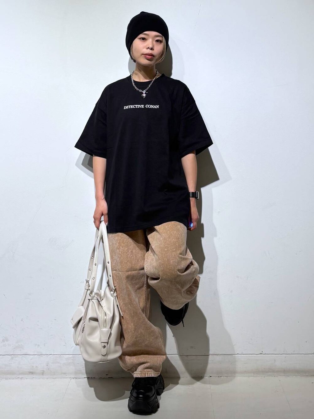 ブラック系のスニーカー、ブラウン系のデニムパンツ、ホワイト系のボストンバッグを着用したレディースの春コーディネートの2枚目の写真