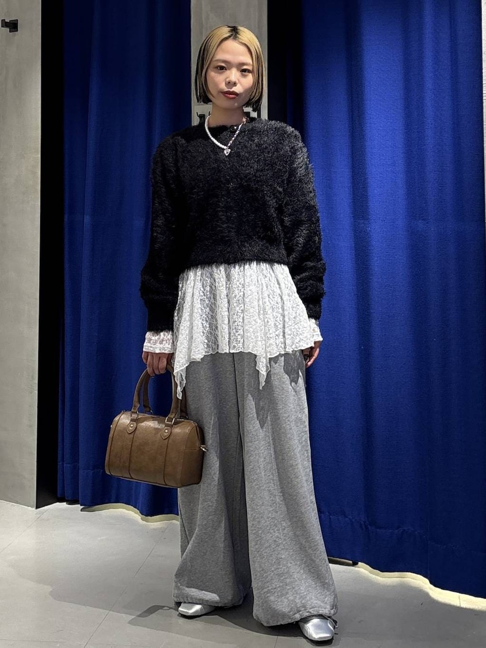 ブラウン系のボストンバッグ、グレー系のスウェットパンツ、シルバー系のスニーカーを着用したレディースの冬コーディネートの3枚目の写真