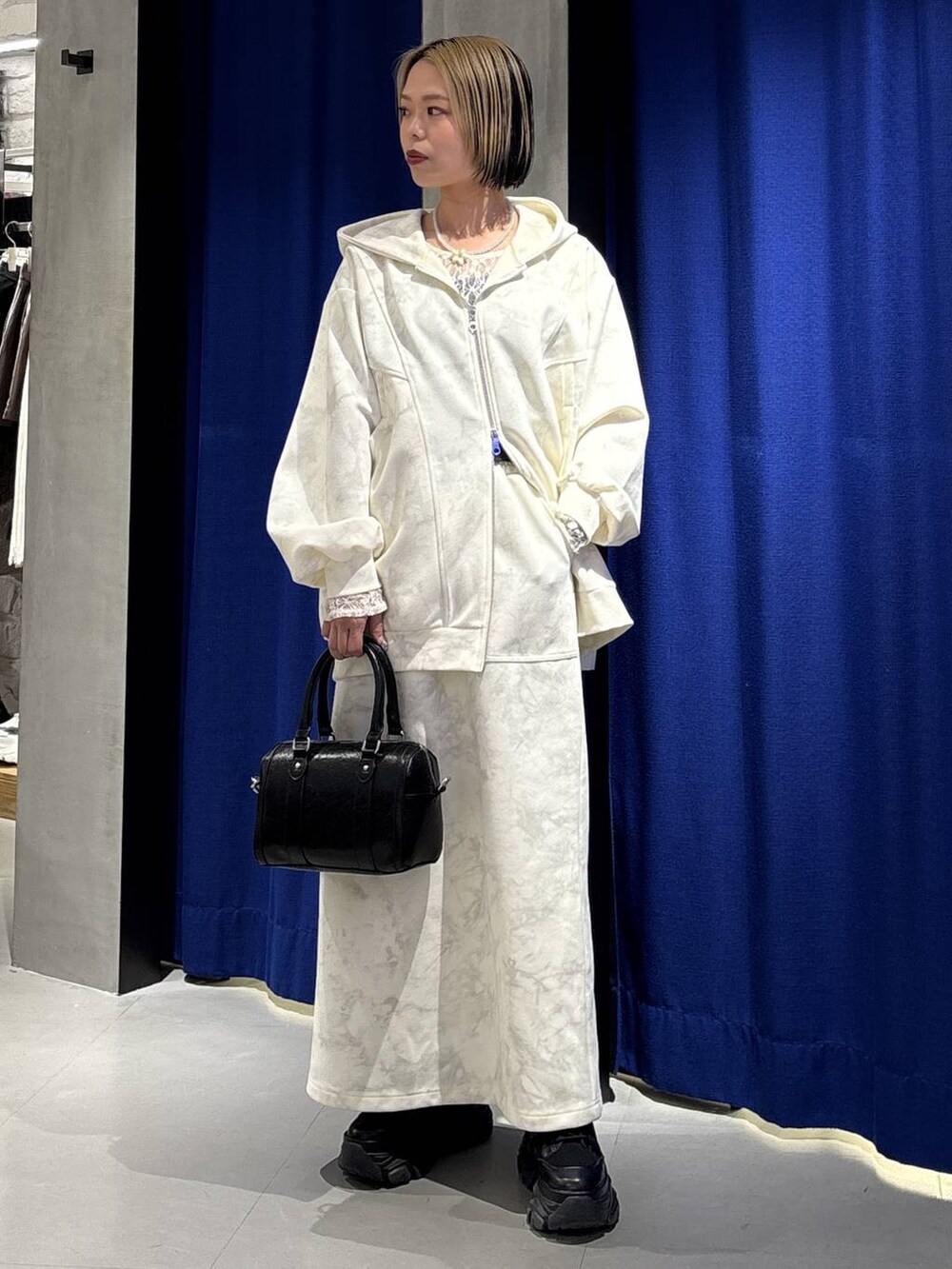 ブラック系のブーツ、ホワイト系のTシャツ/カットソー、ホワイト系のスカートを着用したレディースの冬コーディネートの4枚目の写真