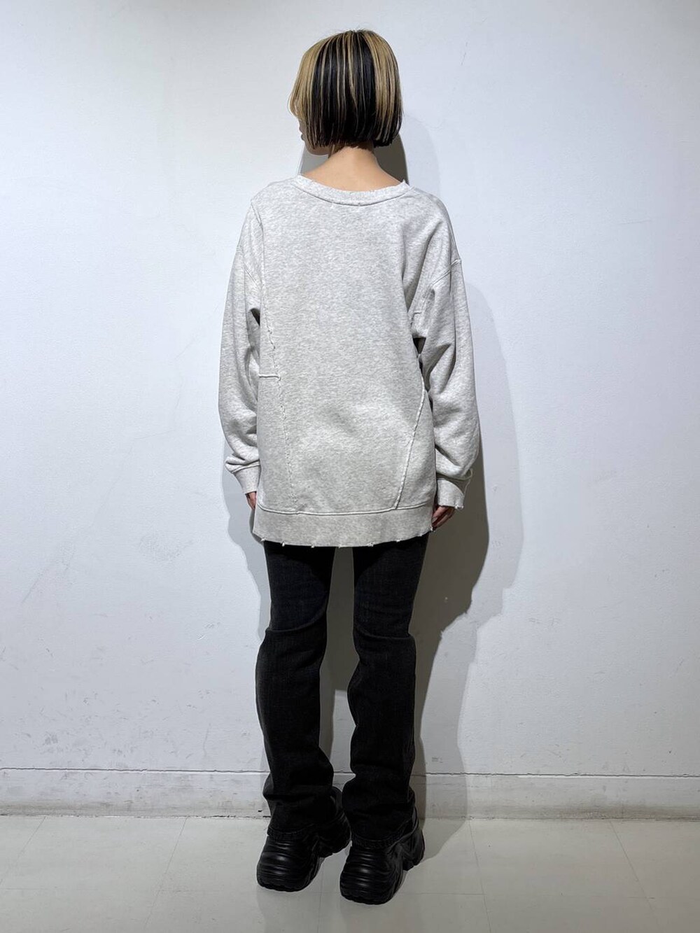 ブラック系のブーツ、ブラック系のデニムパンツ、ベージュ系のスウェットを着用したレディースの秋コーディネートの4枚目の写真