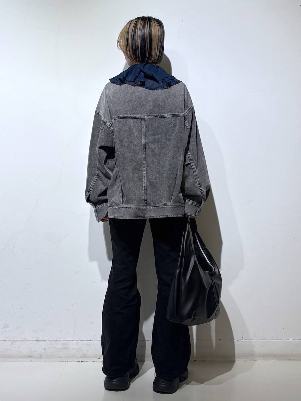 ブラック系のスニーカー、ブラック系のデニムパンツ、ブラック系のブルゾンを着用したレディースの春コーディネートの5枚目の写真