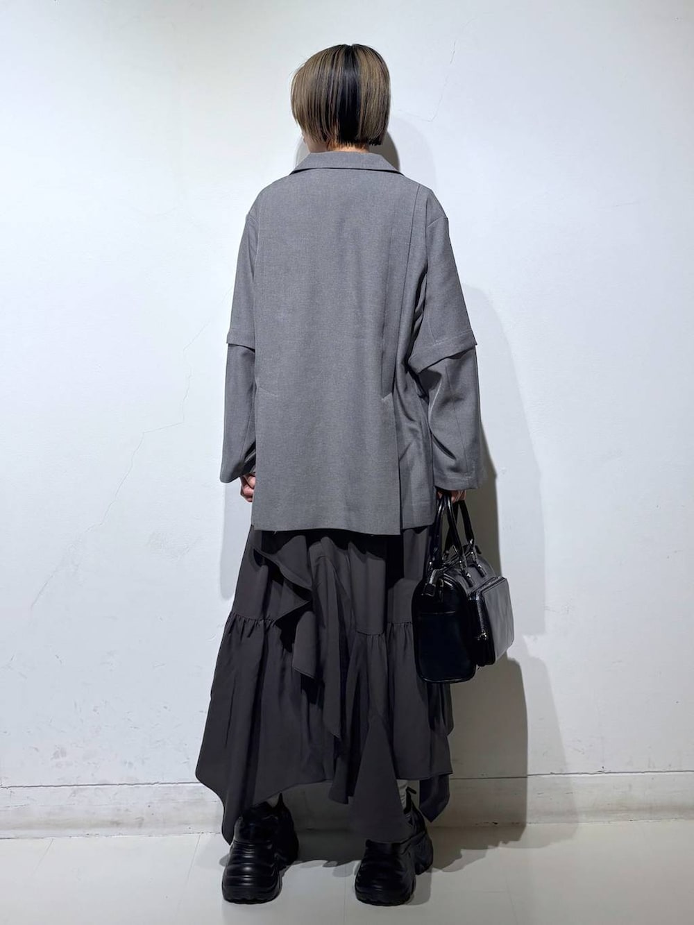 ブラック系のスニーカー、グレー系のスカート、ブラック系のショルダーバッグを着用したレディースの春コーディネートの4枚目の写真