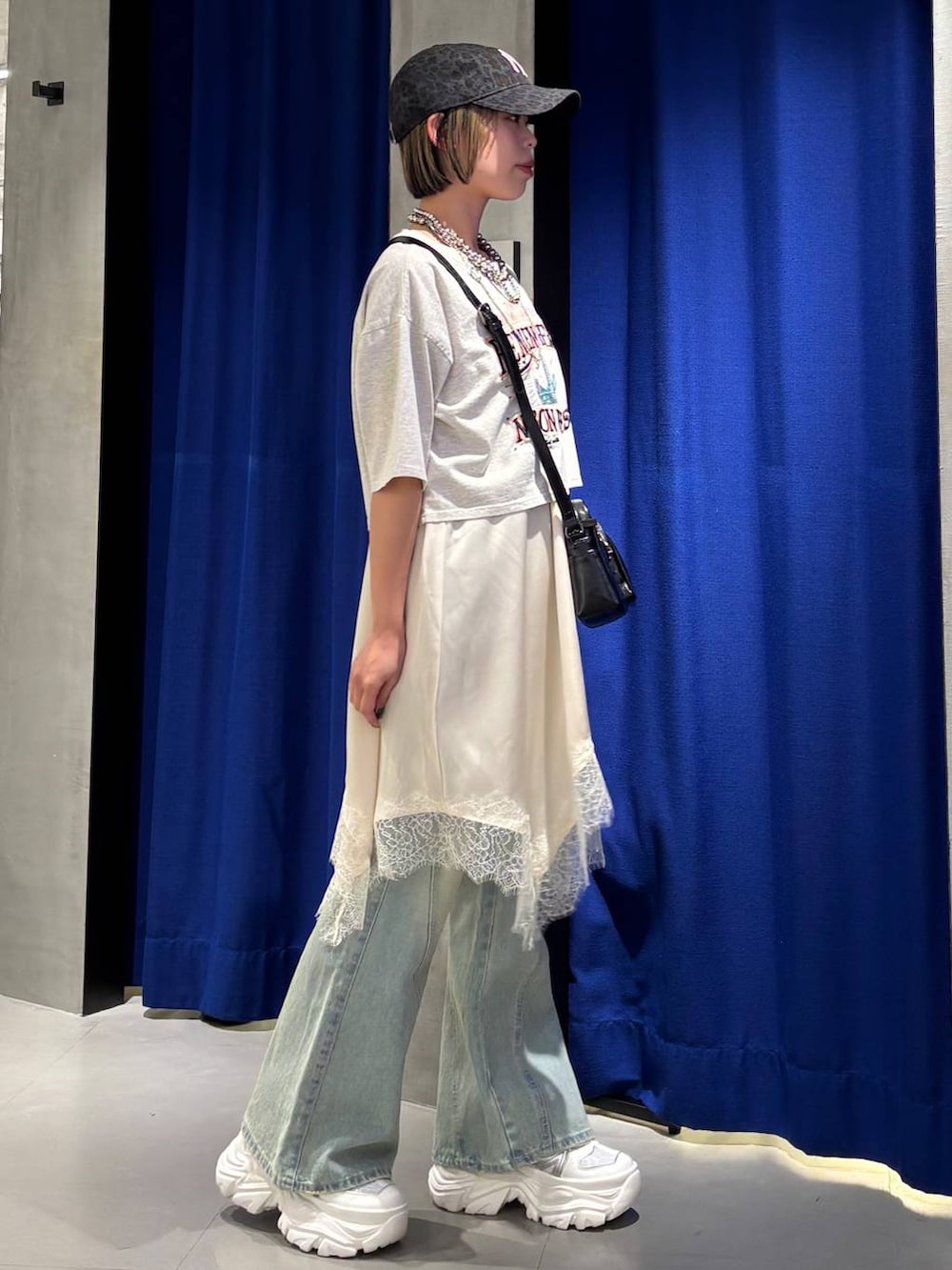 ブラック系のスニーカー、ブルー系のデニムパンツ、ホワイト系のチュニックを着用したレディースの春コーディネートの3枚目の写真