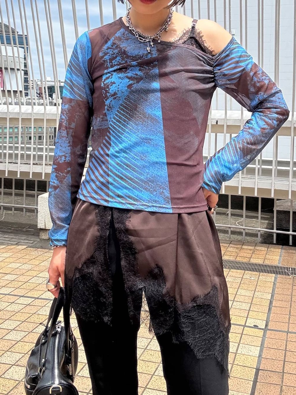 ブラック系のショルダーバッグ、ブラウン系のチュニック、ブラック系のスラックスを着用したレディースの夏コーディネートの6枚目の写真