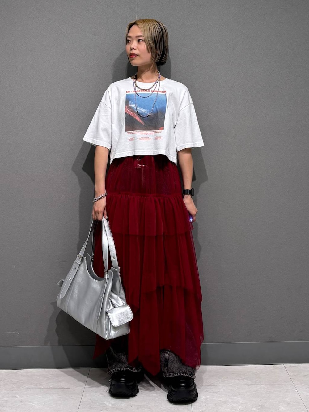 ブラック系のスニーカー、ブラック系のデニムパンツ、ホワイト系のTシャツ/カットソーを着用したレディースの春コーディネートの2枚目の写真