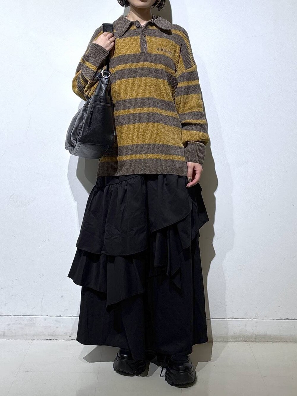 ブラック系のブーツ、ブラック系のボストンバッグ、ブラック系のスカートを着用したレディースの秋コーディネートの2枚目の写真