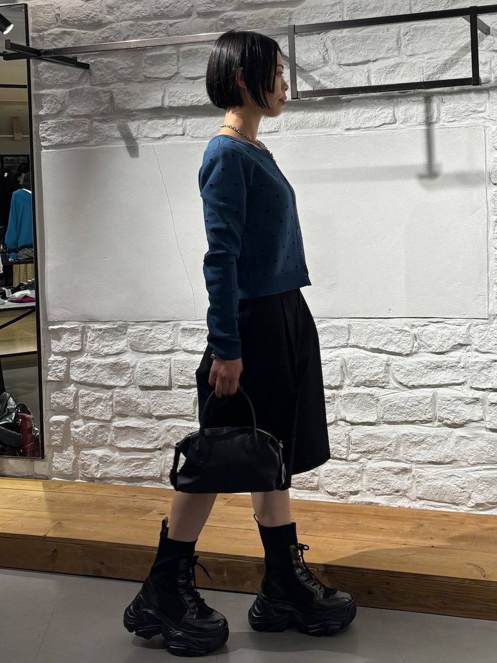 ブラック系のショルダーバッグ、ブラック系のその他パンツ、ブルー系のカーディガン/ボレロを着用したレディースの秋コーディネートの4枚目の写真