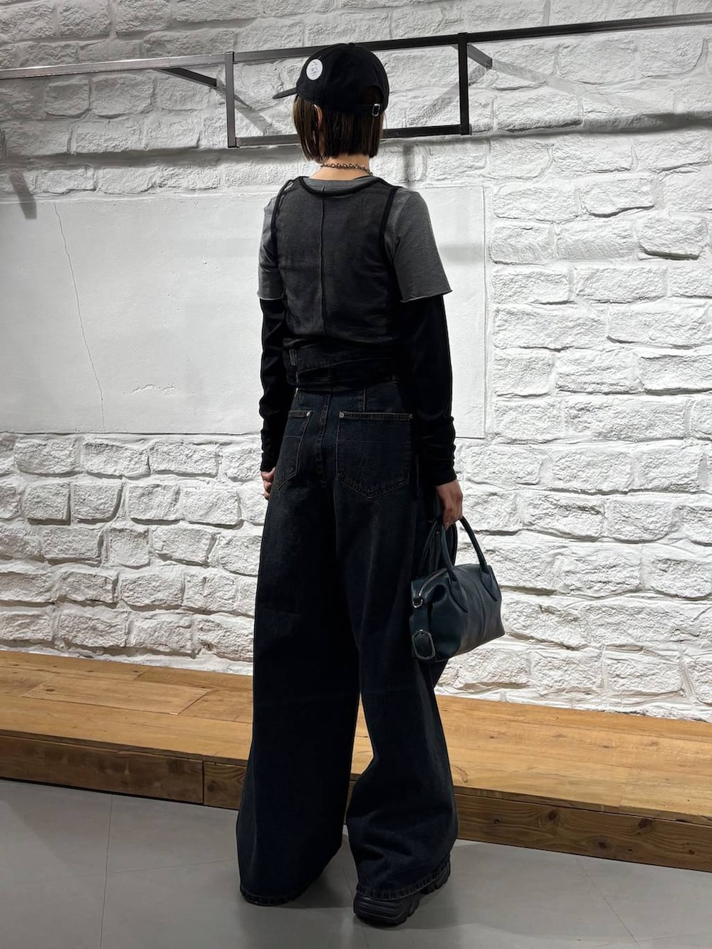 ブラック系のスニーカー、ブルー系のデニムパンツ、ブルー系のショルダーバッグを着用したレディースの秋コーディネートの5枚目の写真