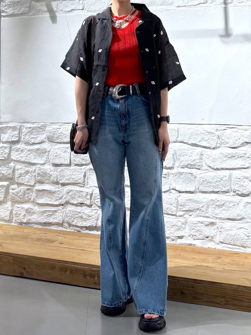 ブルー系のデニムパンツ、ブラウン系のショルダーバッグ、ブラック系のサンダルを着用したレディースの春コーディネートの3枚目の写真