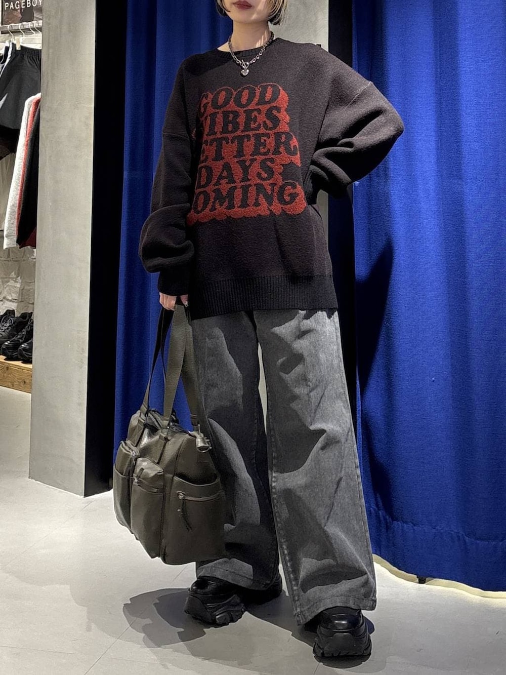 ブラック系のスニーカー、グリーン系のボストンバッグ、ブラック系のニット/セーターを着用したレディースの冬コーディネートの2枚目の写真