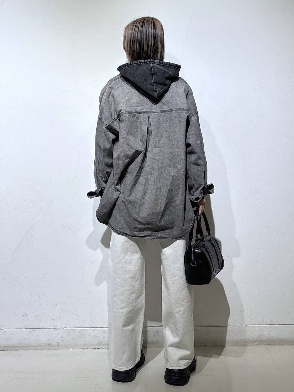 ブラック系のブーツ、ブラック系のTシャツ/カットソー、ホワイト系のスラックスを着用したレディースの冬コーディネートの4枚目の写真