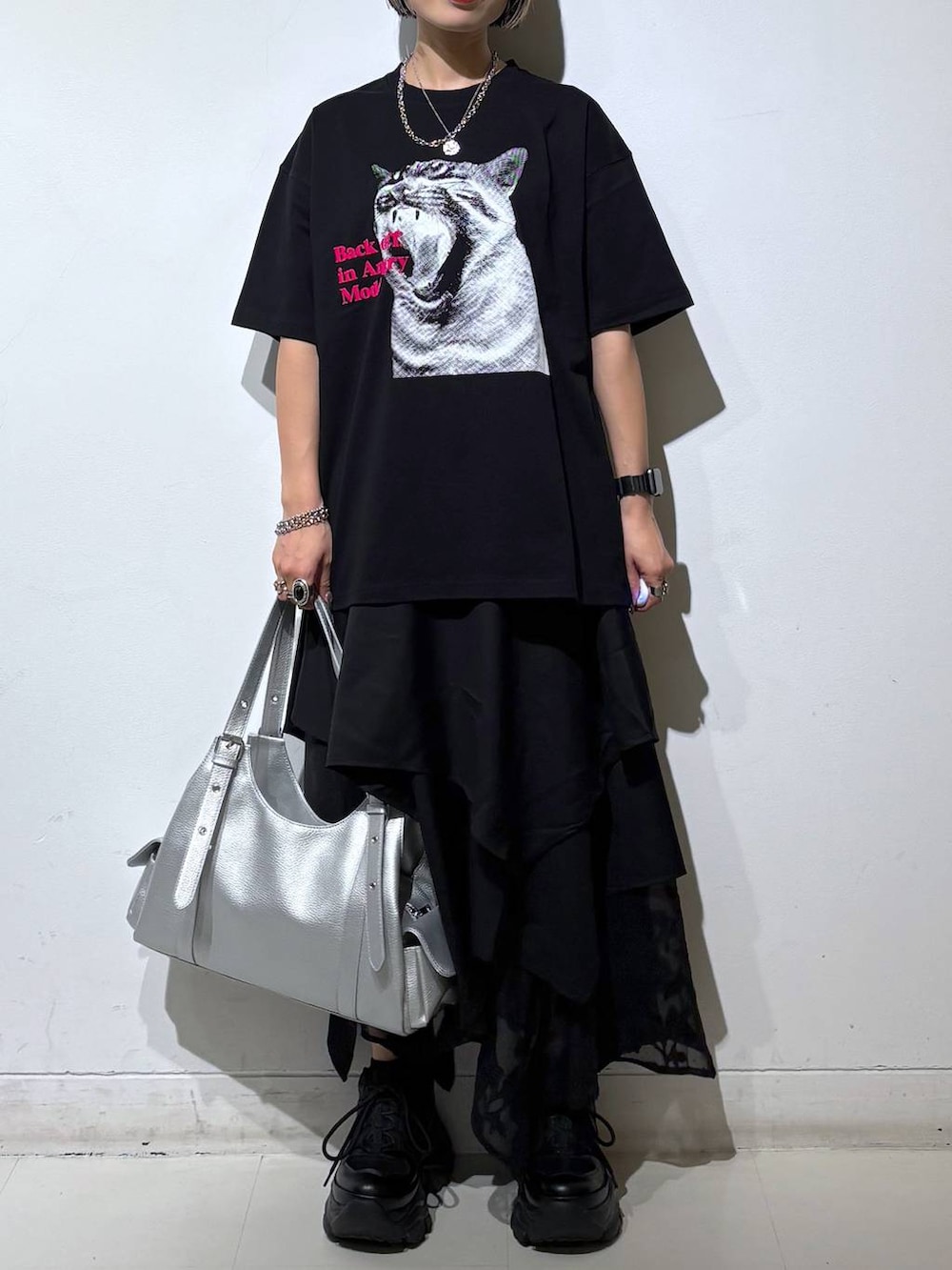 ブラック系のスニーカー、シルバー系のハンドバッグ、ブラック系のTシャツ/カットソーを着用したレディースの夏コーディネートの2枚目の写真