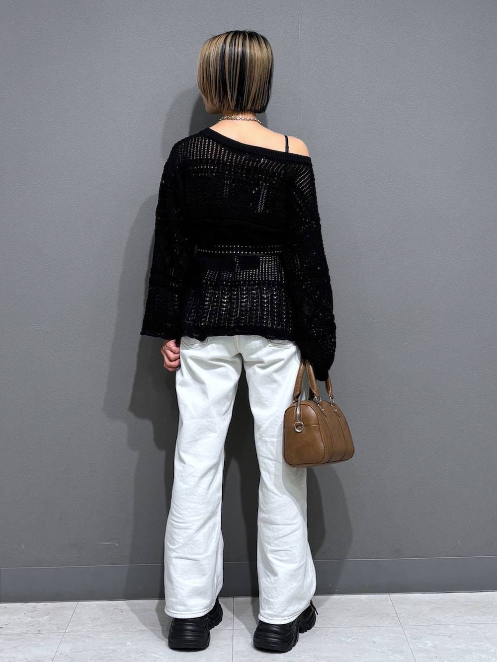 ブラック系のスニーカー、ブラック系のキャミソール、ホワイト系のスラックスを着用したレディースの春コーディネートの5枚目の写真