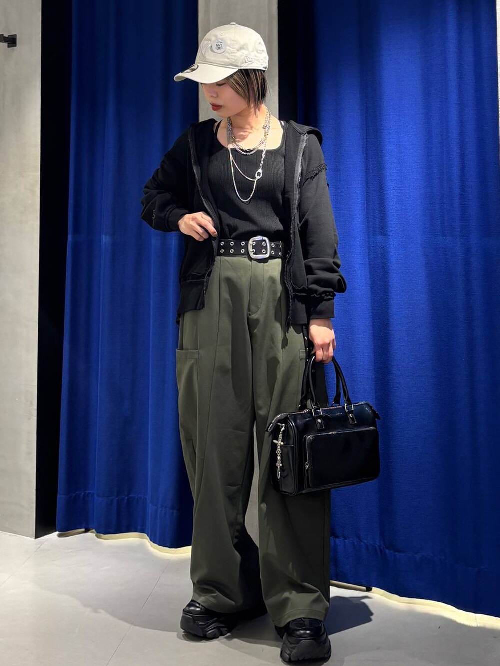 ブラック系のショルダーバッグ、ブラック系のタンクトップ、グリーン系のカーゴパンツを着用したレディースの春コーディネートの2枚目の写真