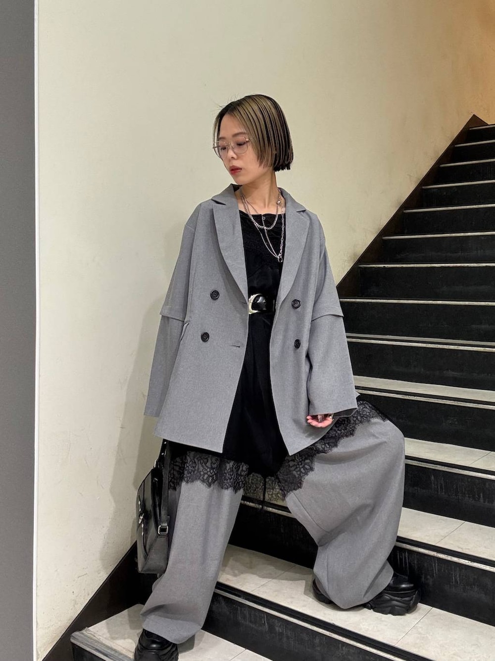 ブラック系のスニーカー、ブラック系のチュニック、ブラック系のハンドバッグを着用したレディースの春コーディネートの3枚目の写真