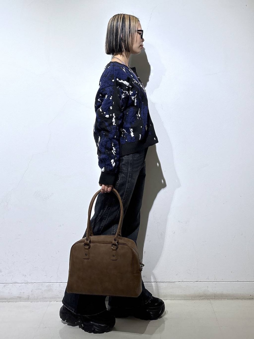 ブラック系のスニーカー、ベージュ系のボストンバッグ、ブルー系のデニムパンツを着用したレディースの冬コーディネートの3枚目の写真