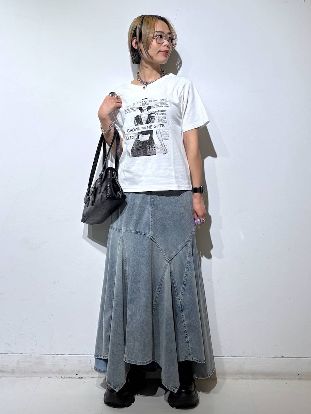 ホワイト系のTシャツ/カットソー、ブラック系のスニーカー、ブルー系のデニムスカートを着用したレディースの夏コーディネートの2枚目の写真