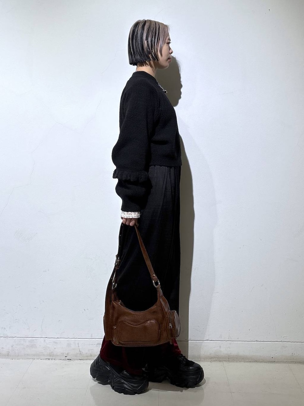 ブラック系のスニーカー、ホワイト系のTシャツ/カットソー、ブラウン系のショルダーバッグを着用したレディースの冬コーディネートの3枚目の写真