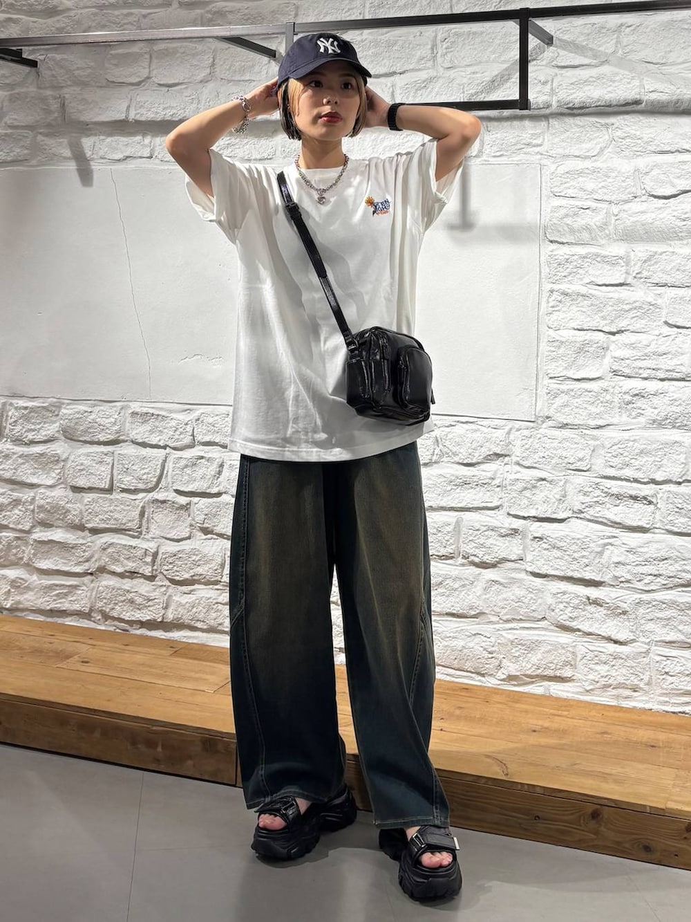 グリーン系のデニムパンツ、ブラック系のショルダーバッグ、グレー系のサンダルを着用したレディースの夏コーディネートの2枚目の写真
