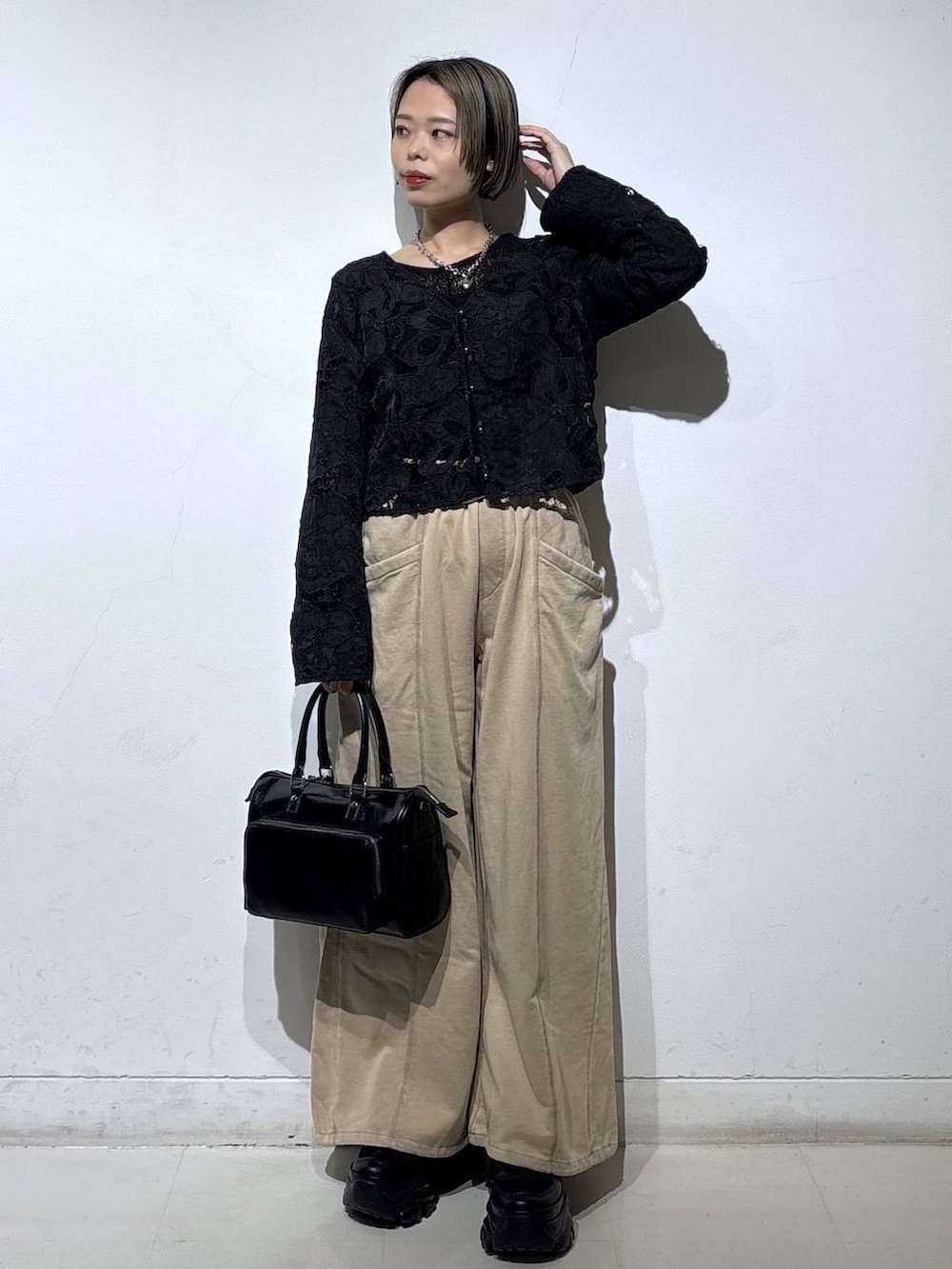 ブラック系のスニーカー、ブラック系のショルダーバッグ、ブラウン系のスウェットパンツを着用したレディースの冬コーディネートの3枚目の写真