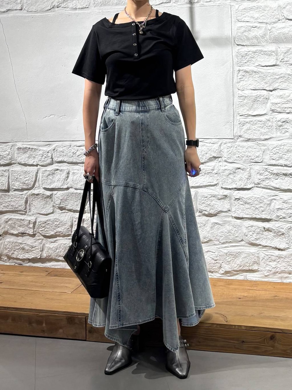 ブラック系のTシャツ/カットソー、ブルー系のデニムスカート、ブラック系のショルダーバッグを着用したレディースの夏コーディネートの3枚目の写真