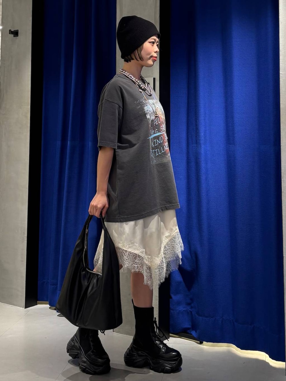 ブラック系のブーツ、ブラック系のトートバッグ、ホワイト系のチュニックを着用したレディースの春コーディネートの5枚目の写真