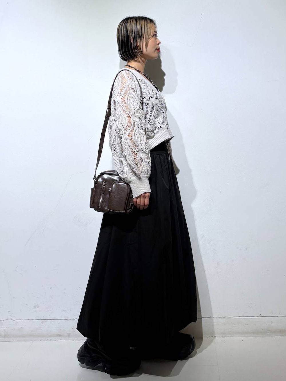 ブラック系のスニーカー、ベージュ系のカーディガン/ボレロ、ブラウン系のショルダーバッグを着用したレディースの春コーディネートの4枚目の写真