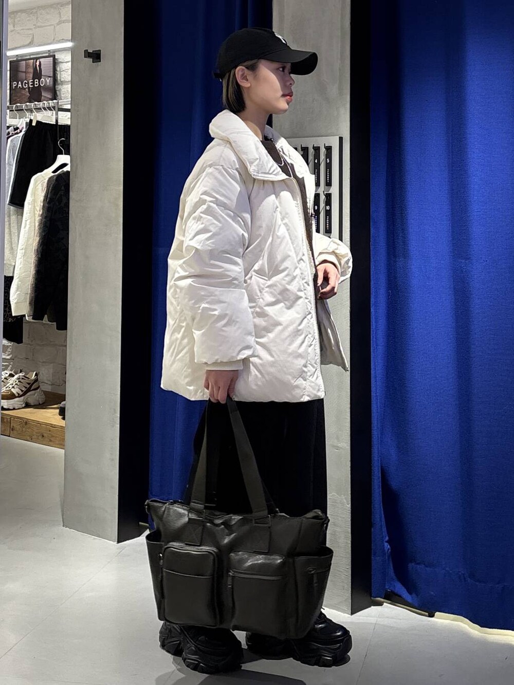 ブラック系のブーツ、グリーン系のボストンバッグ、ホワイト系のブルゾンを着用したレディースの冬コーディネートの4枚目の写真