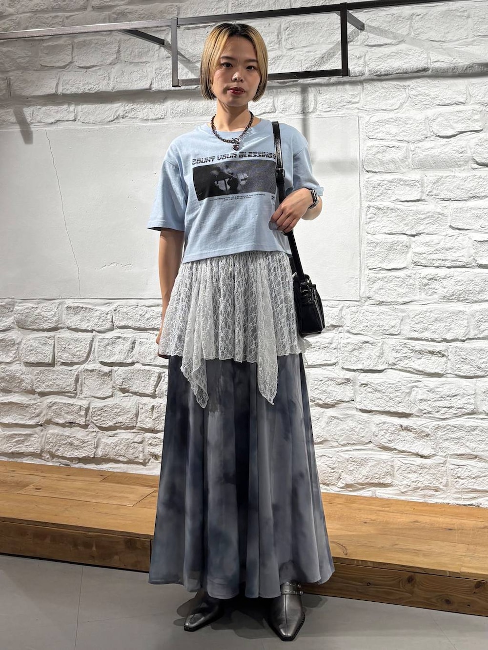 ブルー系のTシャツ/カットソー、グレー系のスカート、ブラック系のショルダーバッグを着用したレディースの夏コーディネートの2枚目の写真