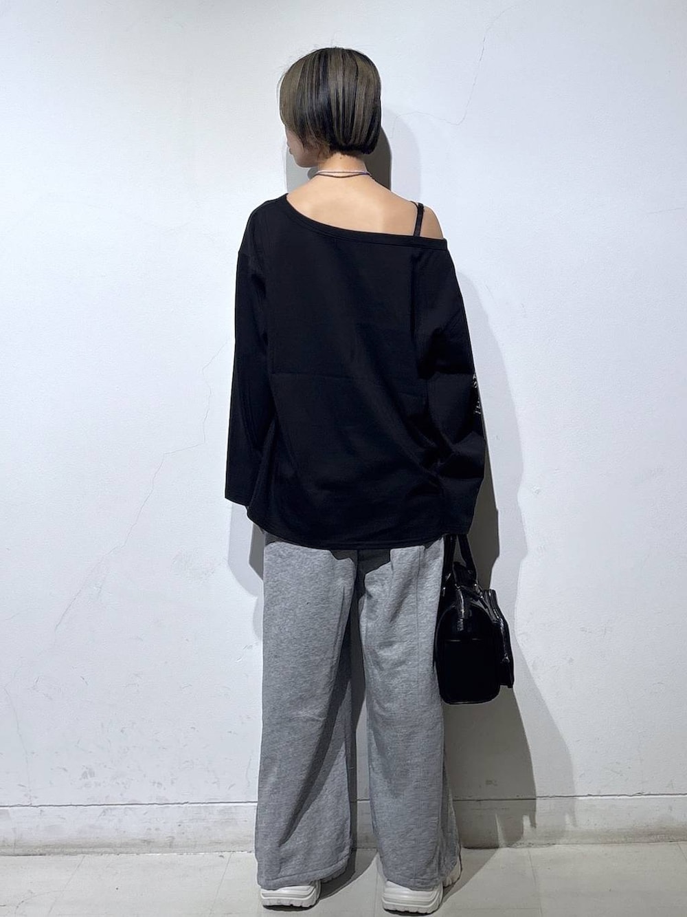 ホワイト系のスニーカー、グレー系のスウェットパンツ、ブラック系のショルダーバッグを着用したレディースの春コーディネートの5枚目の写真