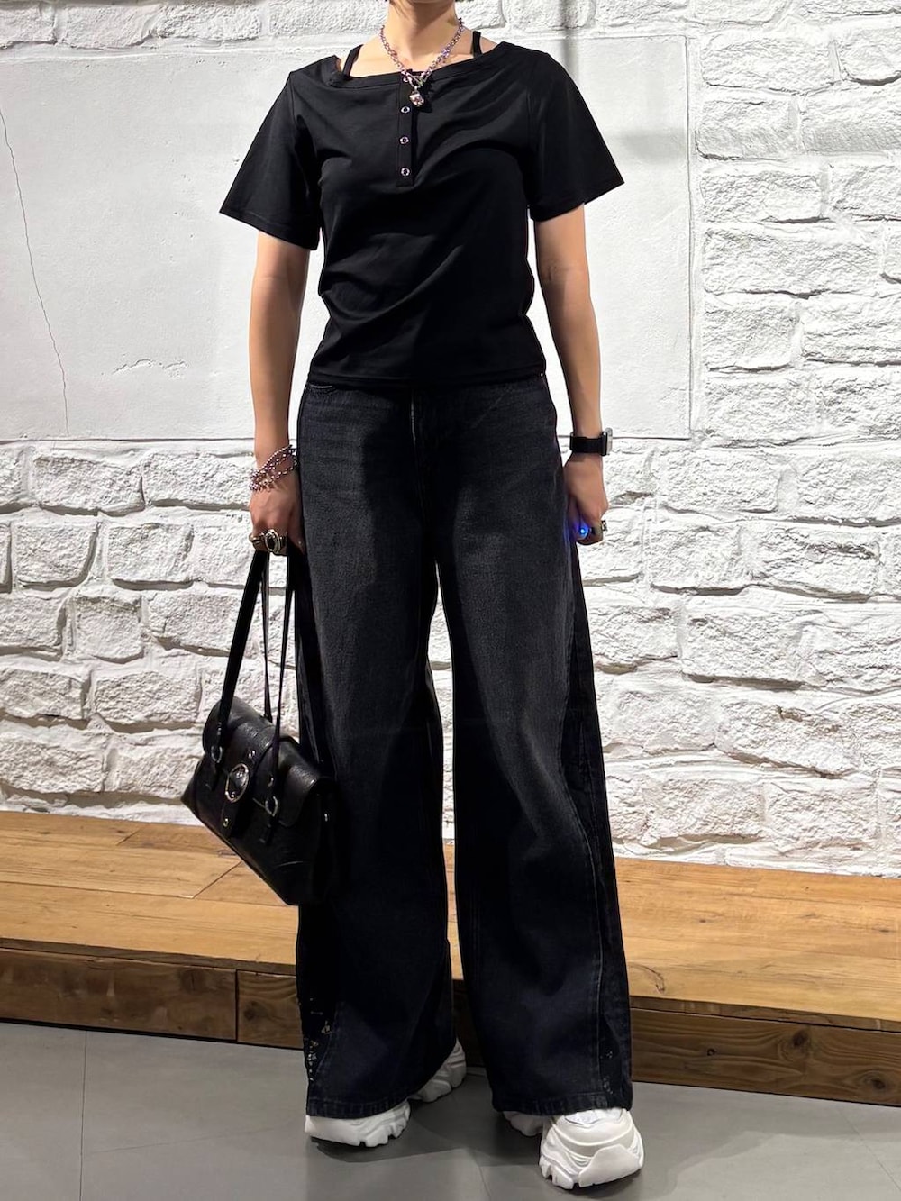 ブラック系のデニムパンツ、ブラック系のTシャツ/カットソー、ホワイト系のスニーカーを着用したレディースの夏コーディネートの3枚目の写真