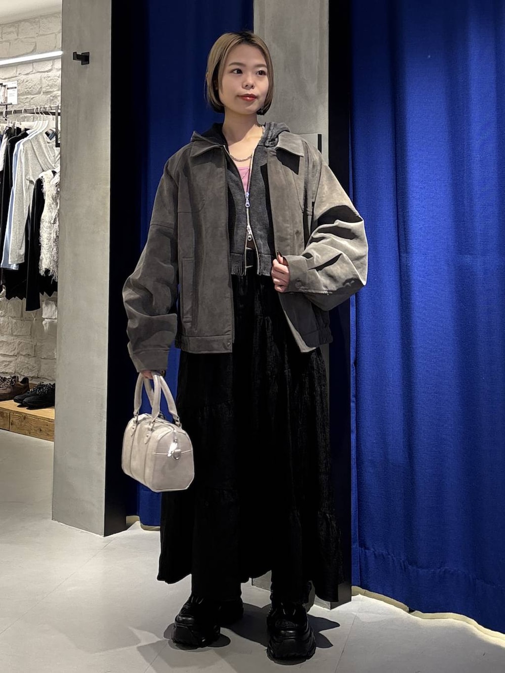 ブラック系のスニーカー、ホワイト系のボストンバッグ、グレー系のパーカーを着用したレディースの冬コーディネートの3枚目の写真