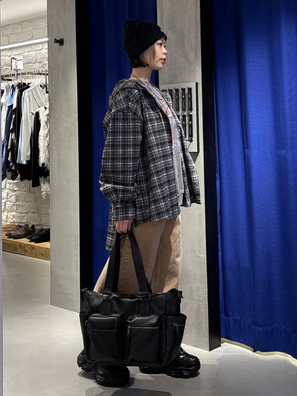 ブラック系のスニーカー、ブラック系のボストンバッグ、ブラウン系のデニムパンツを着用したレディースの冬コーディネートの4枚目の写真