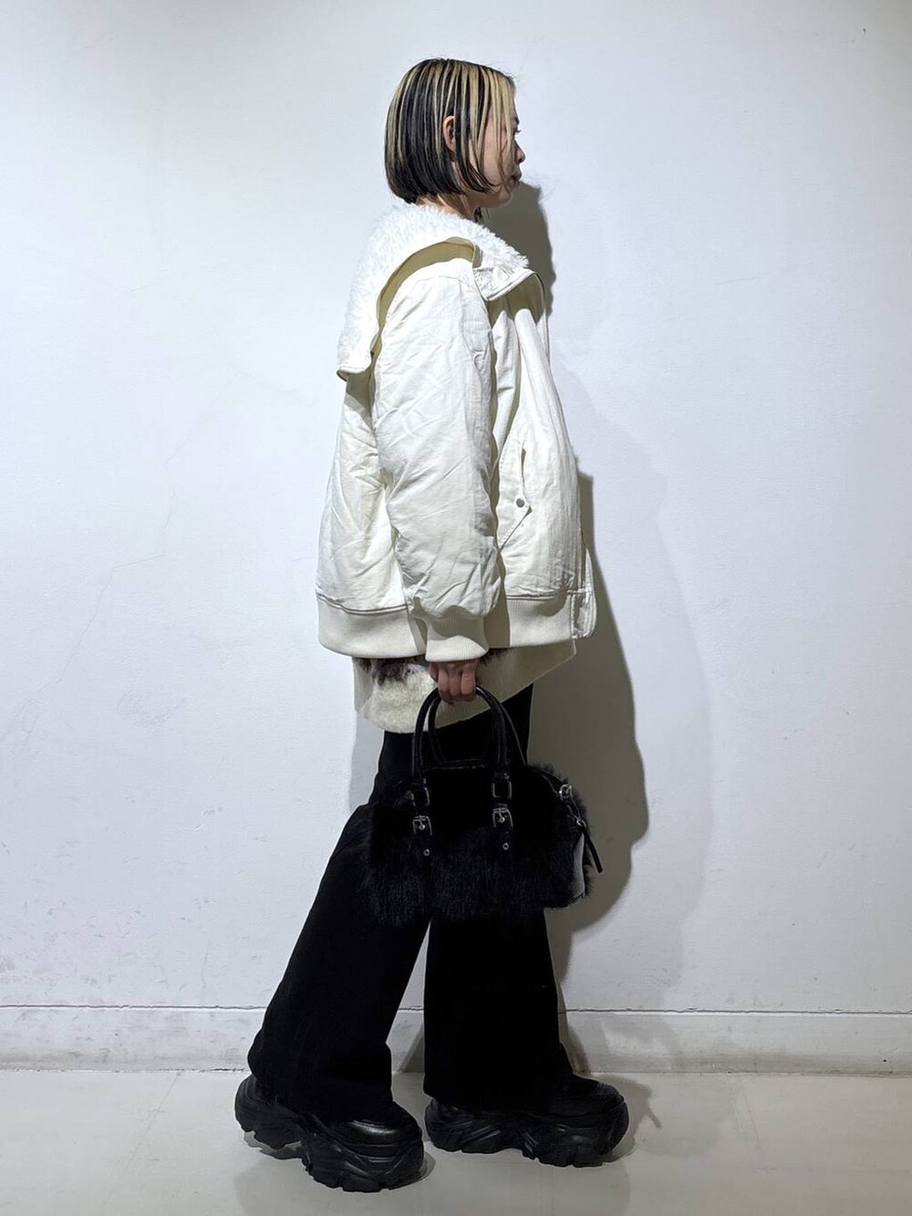 ブラック系のスニーカー、ブラック系のデニムパンツ、ホワイト系のブルゾンを着用したレディースの冬コーディネートの3枚目の写真