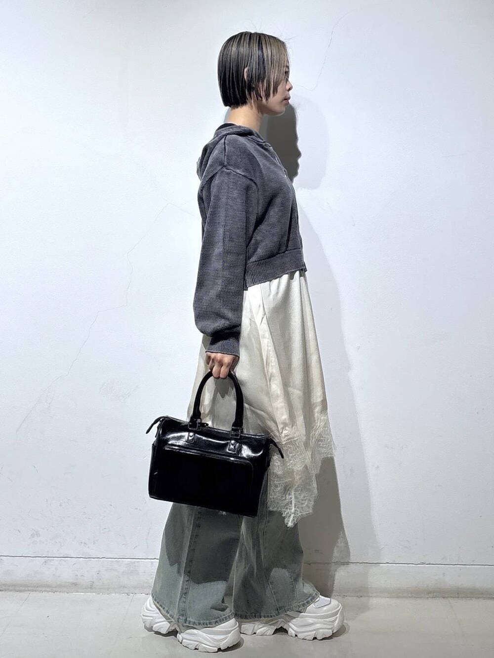 ホワイト系のスニーカー、ブルー系のデニムパンツ、ブラック系のショルダーバッグを着用したレディースの春コーディネートの3枚目の写真