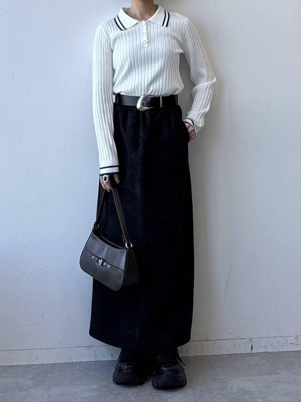 グレー系のスニーカー、ブラック系のスカート、ホワイト系のニット/セーターを着用したレディースの冬コーディネートの3枚目の写真